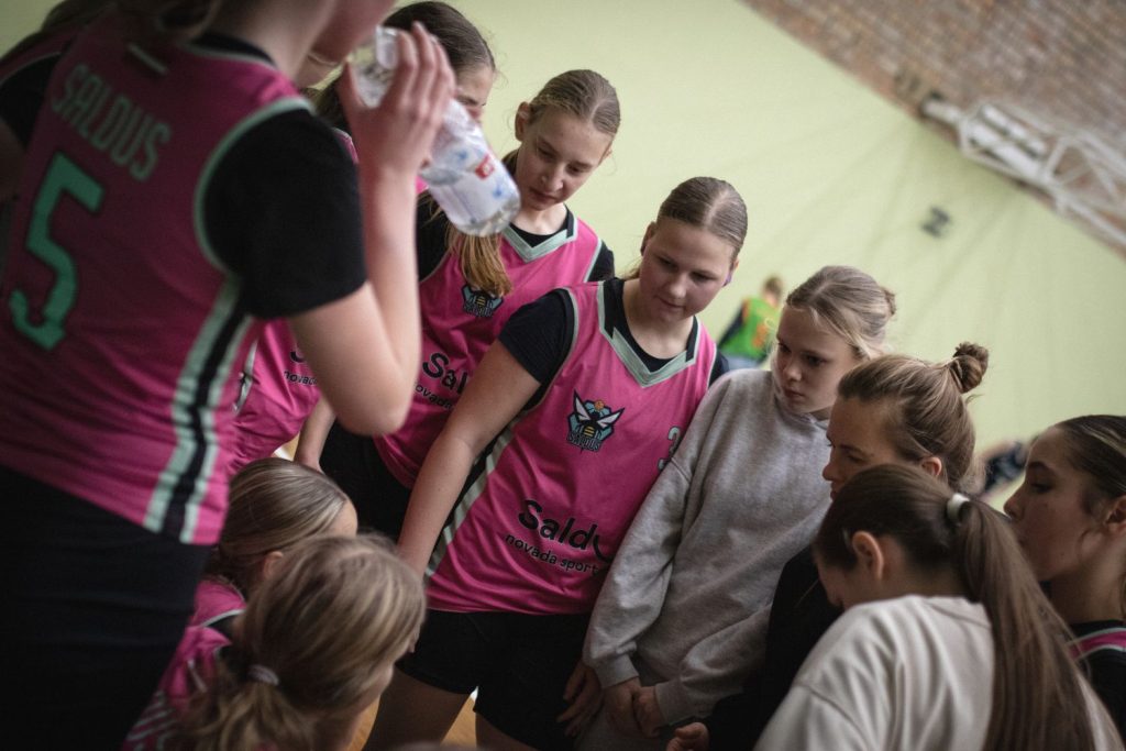 trenere mūsu komandas meitenēm starplaikā dod norādījumus, meitenes ap viņu