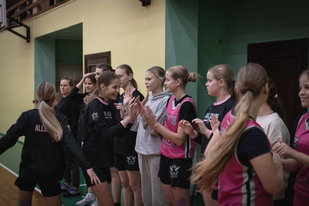 spēles procesā, meitenes gar malu ar rokām sasveicinās ar savām komandas biedrenēm