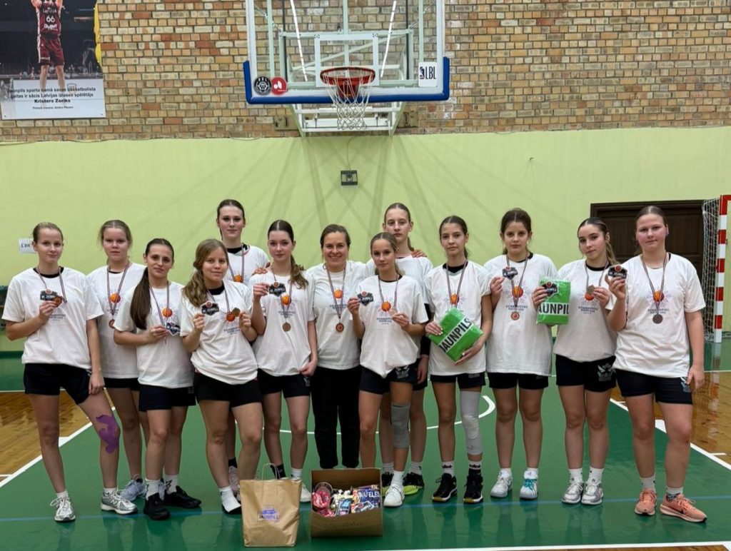 mūsu meiteņu komandas kopīgais foto zem basketbola groza