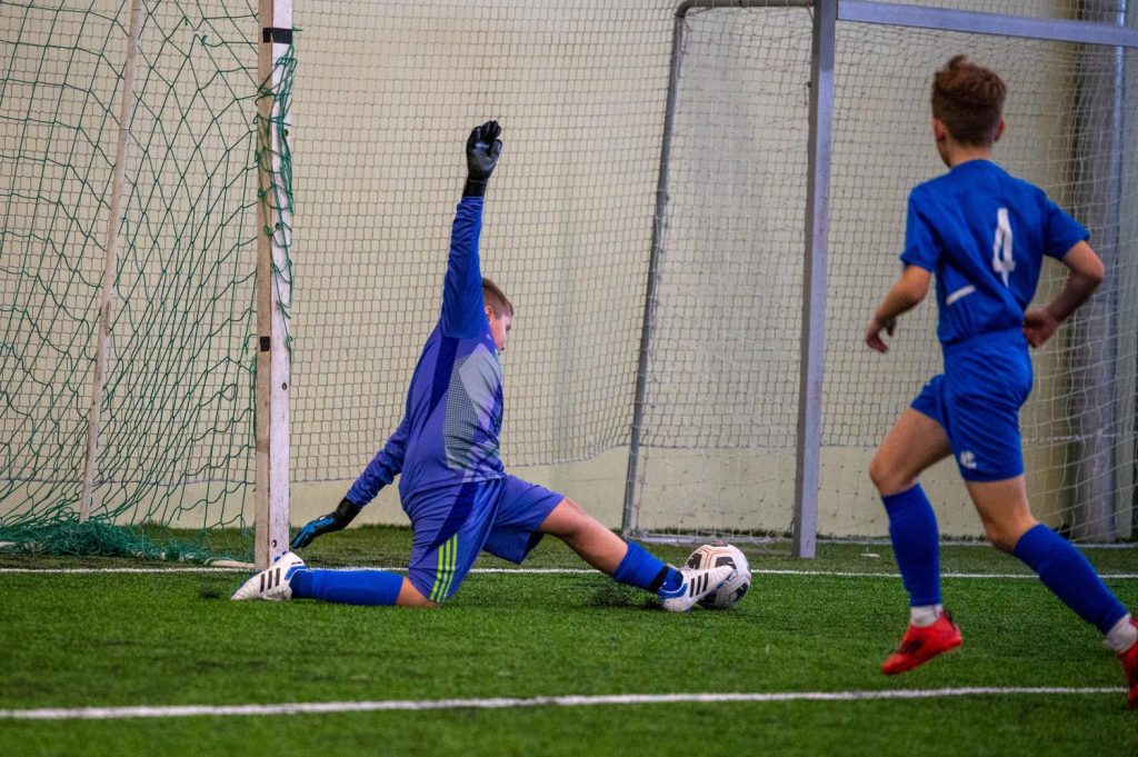 spēles epizode pie vārtiem, vārtsargs mēģina atvairīt sitienu