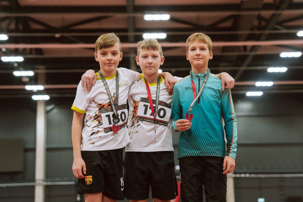 uz pjedestāla mūsu audzēknis ar vēl diviem sportistiem, kaklā medaļas