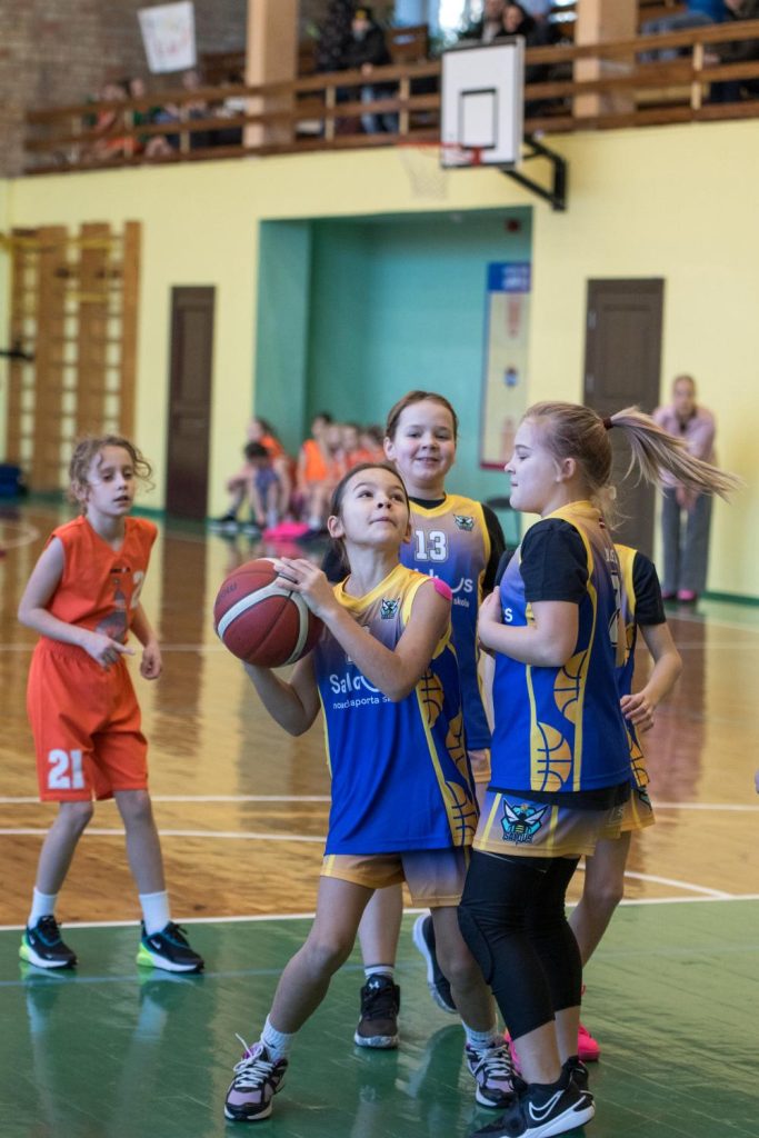 mūsu spēlētāja atvēzējusies un gatavojas mest bumbu uz grozu