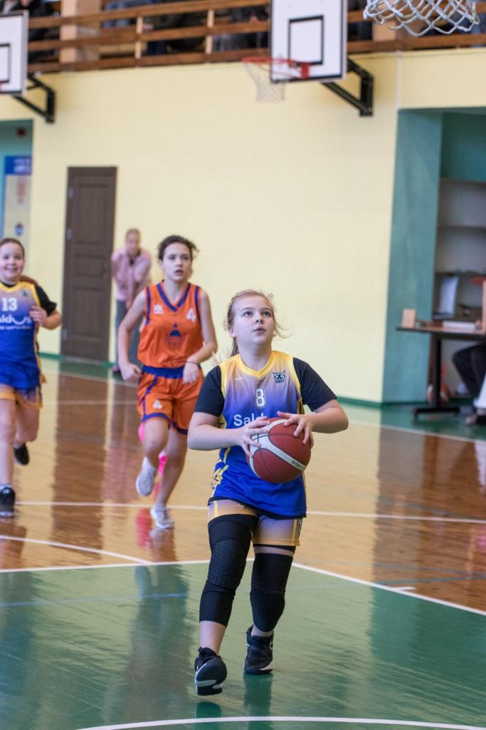 mūsu basketboliste gatavojas mest bumbu grozā