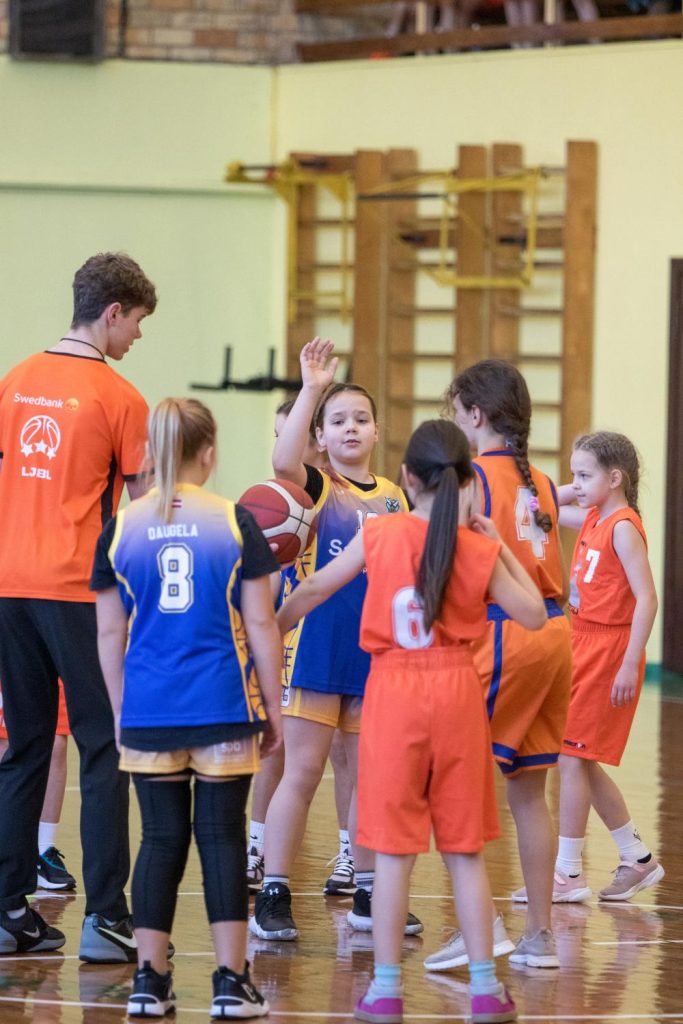 tiesnesim rokās bumba, gatavojas to ievadīt spēlē, apkārt spēlētājas