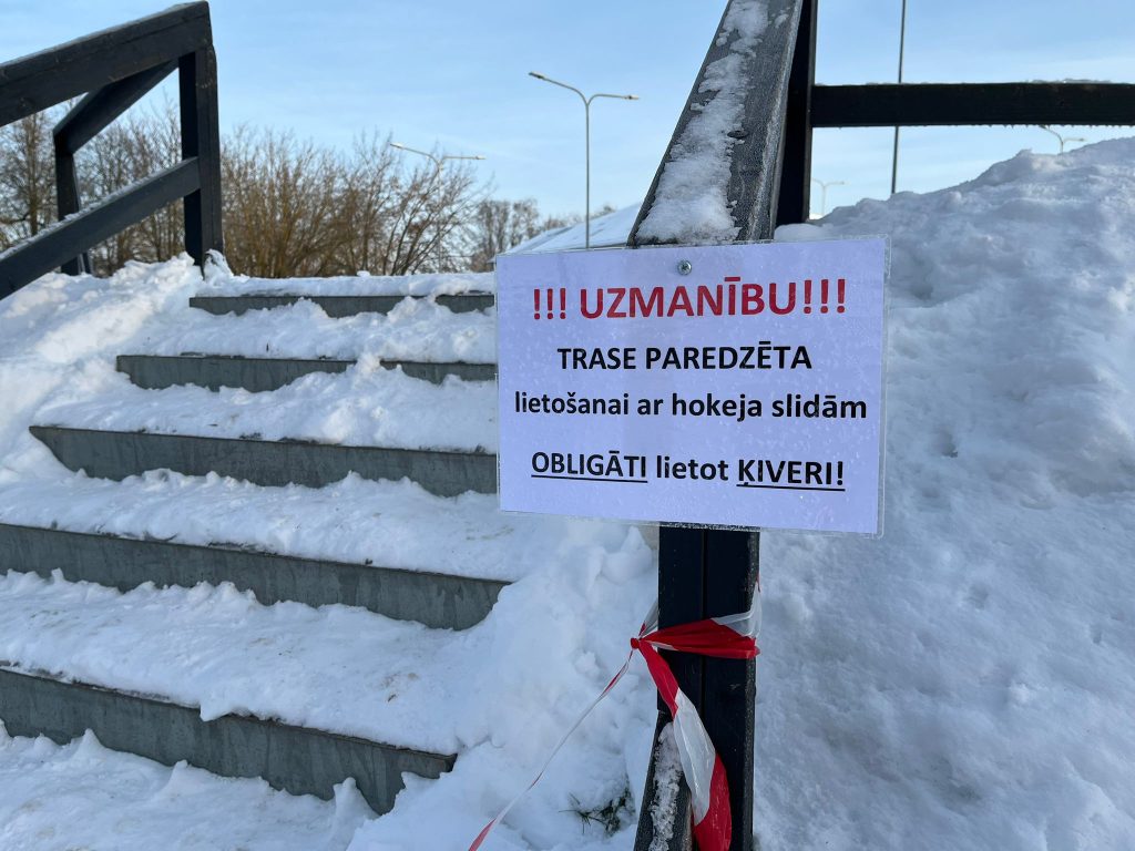 skats uz trepēm, pie kurā ir uzraksts - "Uzmanību! Trase paredzēta lietošanai ar hokeja slidām. Obligāti lietot ķiveri"
