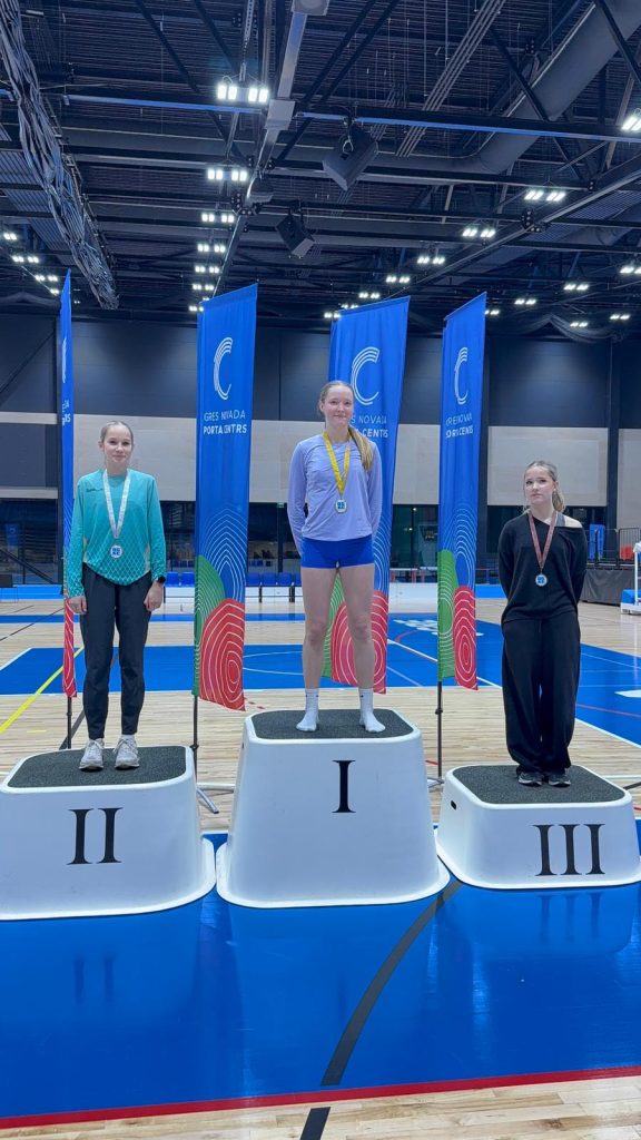 skats uz pjedestālu, uz pakāpieniem medaļnieces