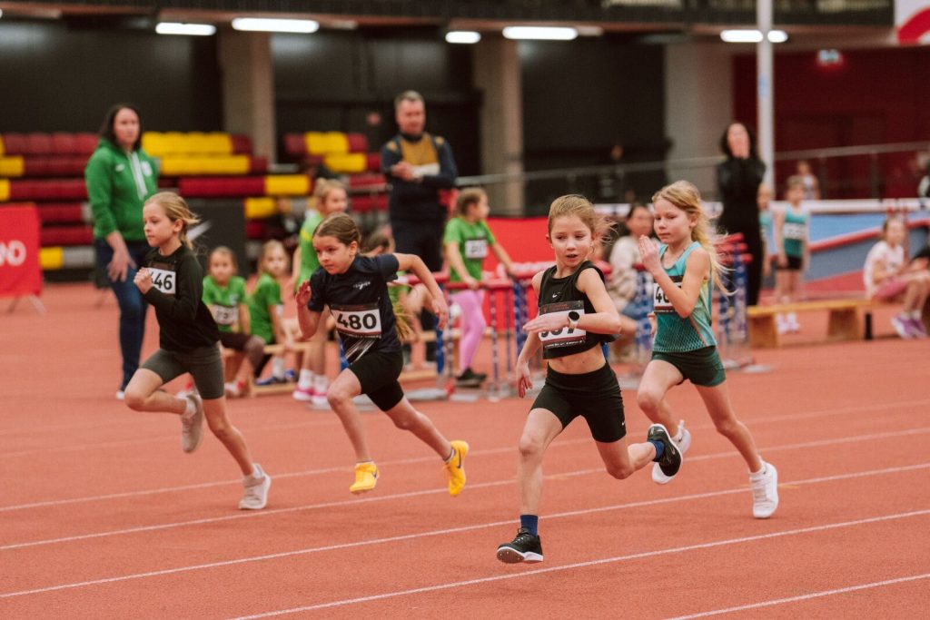 bērni skrien skriešanas sektorā