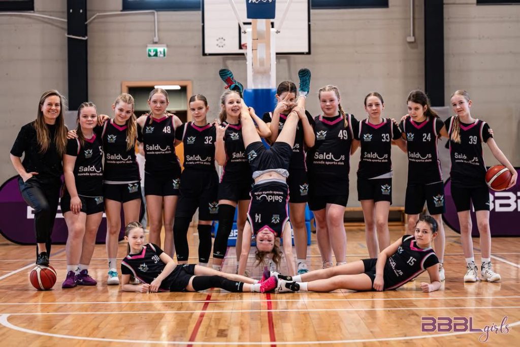 kopbilde ar spēlētājām. priekšplānā viena no spelētājām stāv uz rokām.