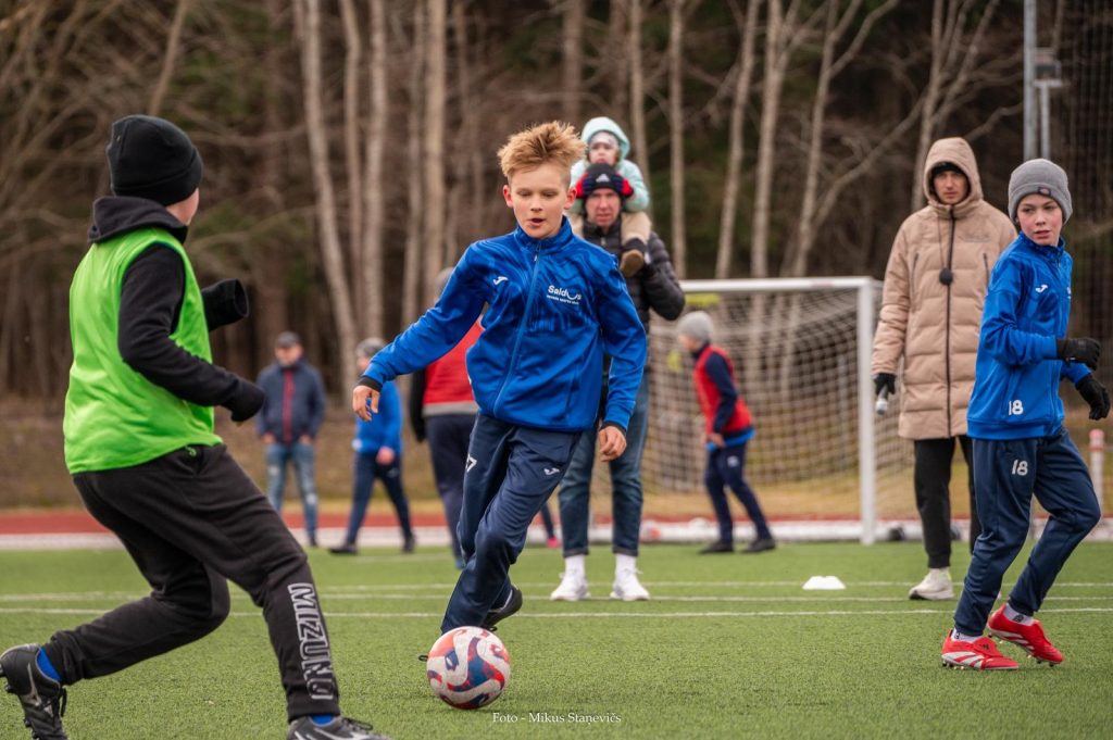 spēles epizode. Malā stāv treneris un vecāki