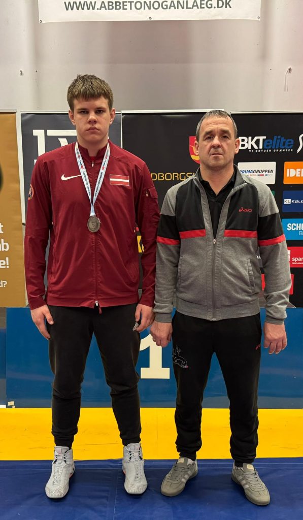 Viesturs ar treneri foto. Viesturam kaklā medaļa