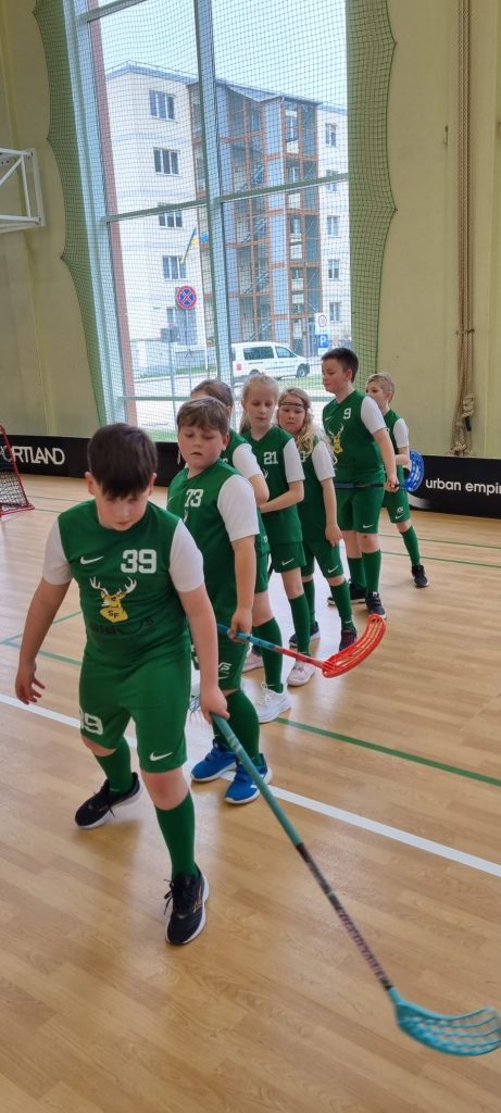 audzēkņi sastājušies rindā ar nūjām