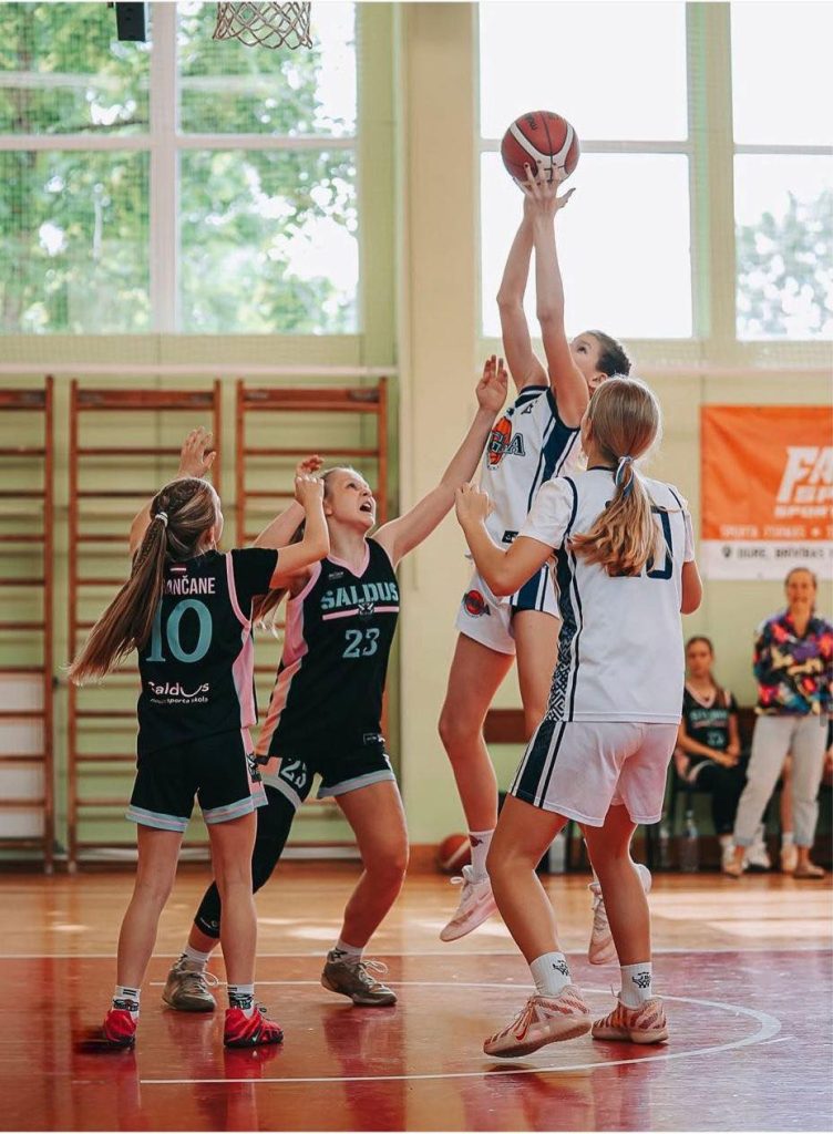 basketbolistes cīnās par bumbu. 2 pretinieces. 2 mūsu audzēknes